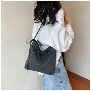 Close-up of gray polka dot hobo shoulder bag with black ribbon bow detail on a model