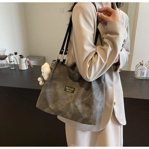 Vue détaillée du sac cabas gris foncé avec étiquette vintage et porte-clé ours