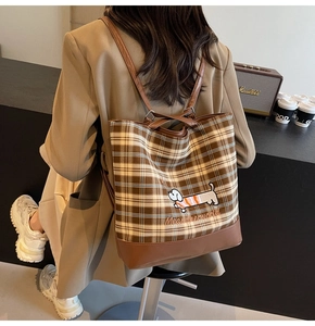 Detail of checkered shoulder bag featuring embroidered dachshund and leather base