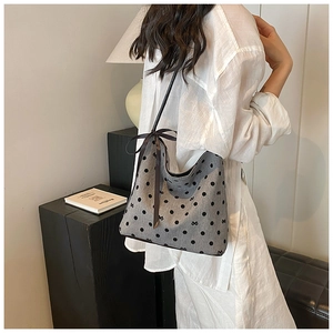 Close-up of a grey canvas bucket bag with black polka dots and decorative ribbon bows