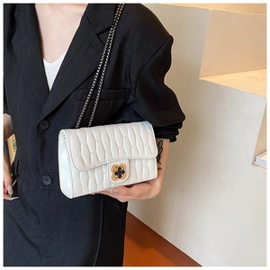 Close-up of white quilted chain bag with gold clover clasp and textured PU leather finish