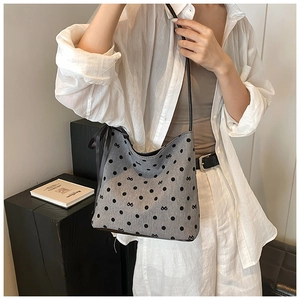 Detail of grey polka dot fabric bag with silk ribbon bow and black shoulder strap