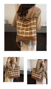 Detail of checkered canvas bag featuring dog embroidery and leather strap texture