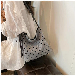 Detail of grey bucket bag with black polka dots and decorative ribbon side ties