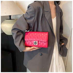 Detail of rose red quilted crossbody bag with golden flower clasp and chain strap