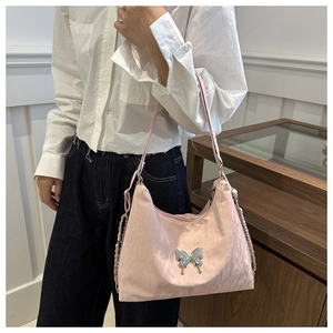 Close-up of pink hobo bag featuring embroidered texture and a silver metal butterfly