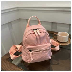 Detailed view of a pink mini canvas backpack on a coffee table in a minimalist room