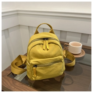 Detailed view of yellow mini canvas backpack with top handle and woven strap detail