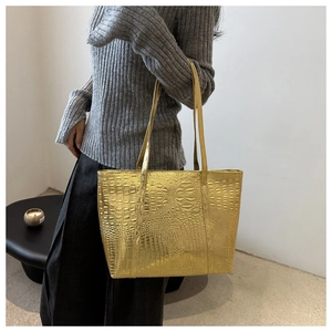 Detailed view of large gold tote bag with crocodile pattern and polished metallic finish