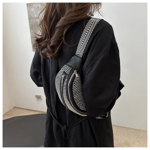 Detail of black crossbody chest bag with sparkling rhinestones and wide woven strap