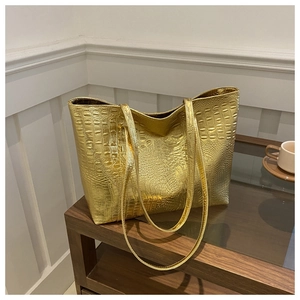 Macro detail of glossy gold crocodile pattern leather texture on large tote bag