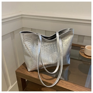 Silver large capacity tote bag with crocodile texture and metallic finish on wooden table