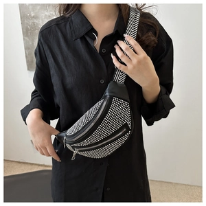 Detail of black crossbody bag with silver studs and chevron wide strap worn on chest