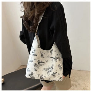 Close-up of white underarm bag with black butterfly and star pattern on wide strap