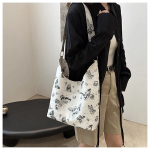 Detailed shot of an ivory hobo bag with black butterfly prints on a wide shoulder strap