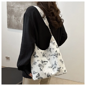 Detail of white tote bag featuring black butterfly print and wide shoulder strap design