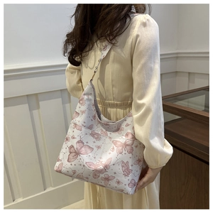 Close-up of white shoulder bag with pink butterfly prints worn on a model's shoulder