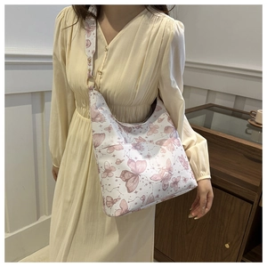 Detail of white moon tote bag featuring pink butterfly prints and wide shoulder strap