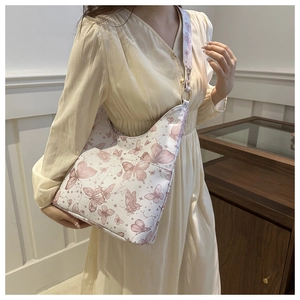 Detail of white tote bag with butterfly prints and wide shoulder strap on model