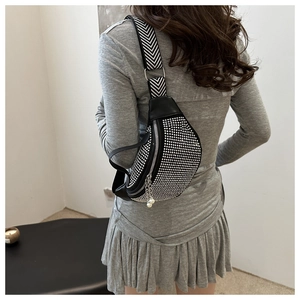 Detail of sequin rhinestone waist bag with pearl pendant and patterned strap worn by a model