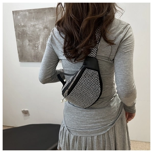 Close-up of a black rhinestone crossbody bag with pearl zipper and patterned strap