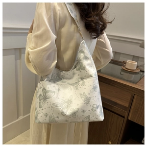 Minimalist white tote bag with green butterfly print shown on a model in home setting