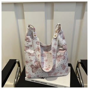 Detail of white tote bag featuring pink butterfly prints and gold metal ring hardware