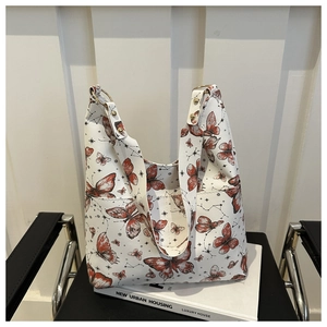 Detail of white litchi-textured tote bag with red butterfly print and gold hardware