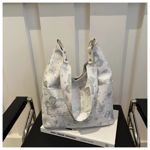 Close-up of white butterfly print tote bag with gold ring hardware and star patterns