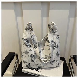 Detail of white tote bag with black butterfly prints and gold metal ring hardware