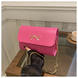 Detail of rose pink crossbody bag with gold bow clasp and elegant chain strap for women