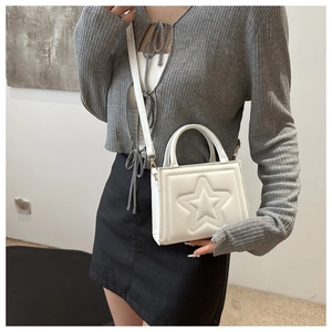 Detail of white star embossed square handbag shown on shoulder by model in close-up shot