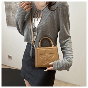 Detail of khaki square crossbody bag with embossed star design and adjustable strap