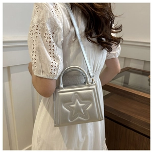 Silver mini square bag with embossed star pattern worn by model in elegant indoor setting