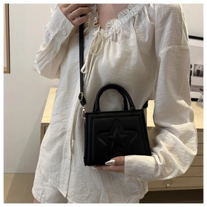 Detailed view of black mini crossbody bag with embossed star pattern on stylish model