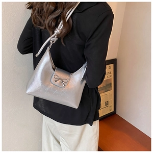 Detail showing metallic silver shoulder bag with bow buckle on a model's shoulder
