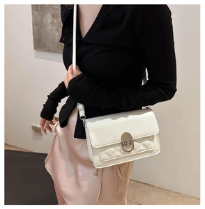Detail of white quilted crossbody bag featuring a golden oval twist lock and sleek leather strap