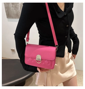 Detail of rose pink quilted crossbody bag with silver buckle worn by a model