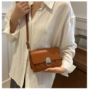 Détail d'un sac à bandoulière matelassé marron avec boucle argentée porté par un mannequin