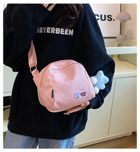 Detail of pink nylon crossbody bag with star plush charm and Luck You patch