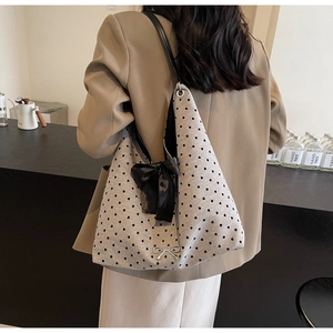 Detail of grey knit tote bag with heart pattern and elegant black satin ribbon bow