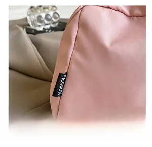 Close-up of pink nylon bag with embroidered purple mushroom and black fashion label tag