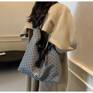 Detail showing the gray heart-print tote with satin bow and silver metal butterfly accent