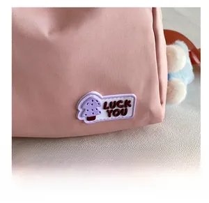 Detail of pink nylon bag with Luck You rubber patch and blue plush ball pendant