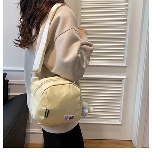 Detail of a beige oxford shell bag with fashion tags and a cute luck patch on the side