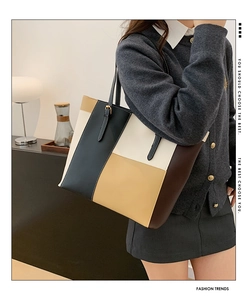 Detail of a color-block patchwork PU leather tote bag with elegant golden hardware