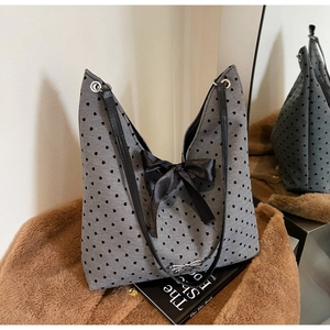 Detail of grey tote bag with heart patterns and large black bow decoration