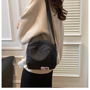 Detail of black nylon crossbody bag with Lucky You patch and white plush star pendant