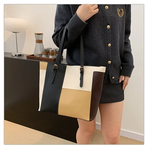 Detail of color-block PU leather tote bag with gold buckle on adjustable handle