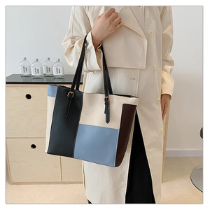 Detail of color-block tote bag with slim handles shown on a beige trench coat model